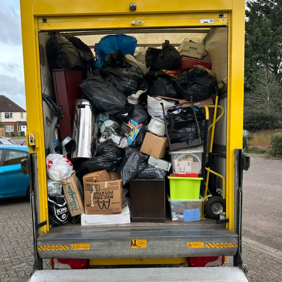 House clearance load with bags, boxes and furniture in the back of the van